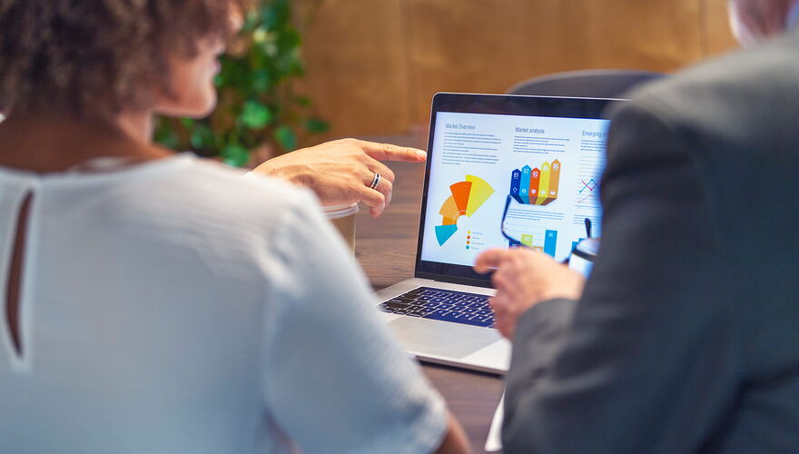 Zwei Personen schauen sich eine Grafik auf einem Laptop an